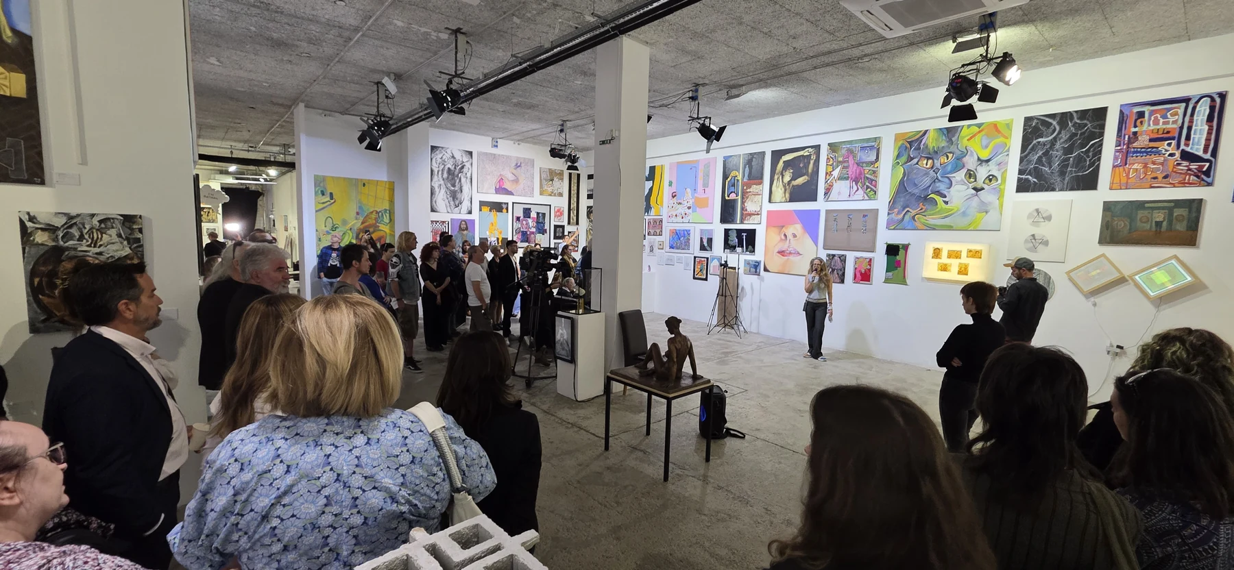 Laczkovich Borbála mikrofonos köszöntője a Godot Art Expo közönsége előtt.